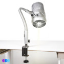A silver, adjustable Aerovex Sunflower II LED Nail Dust Collector is clamped to the edge of a white desk. Three overlapping colored circles appear in the lower left corner. Read more at Aerovex Systems (aerovexsystems.com)