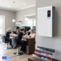 A nail salon with three people receiving manicures at black chairs and tables. A white air purifier unit is mounted on the wall. Below it, shelves display various colorful nail polishes. Pendant lights hang from the ceiling, and a window lets in natural light. Read more at Aerovex Systems (aerovexsystems.com)