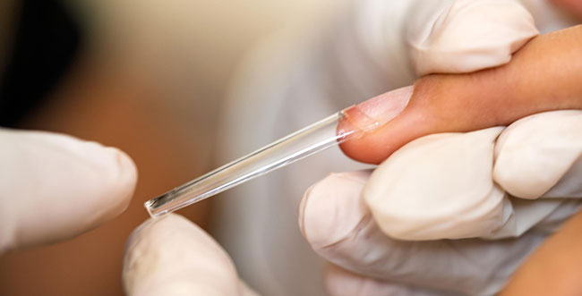 A close-up of gloved hands applying a clear extension tip to a person's fingernail, highlighting careful placement for a nail enhancement. Proper source capture ventilation reduces inhalation risks during hair and nail services like this. Read more at Aerovex Systems (aerovexsystems.com)